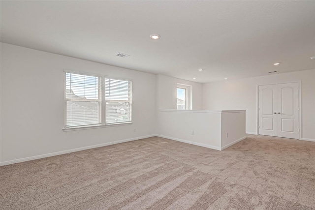 spare room featuring light colored carpet, recessed lighting, baseboards, and visible vents