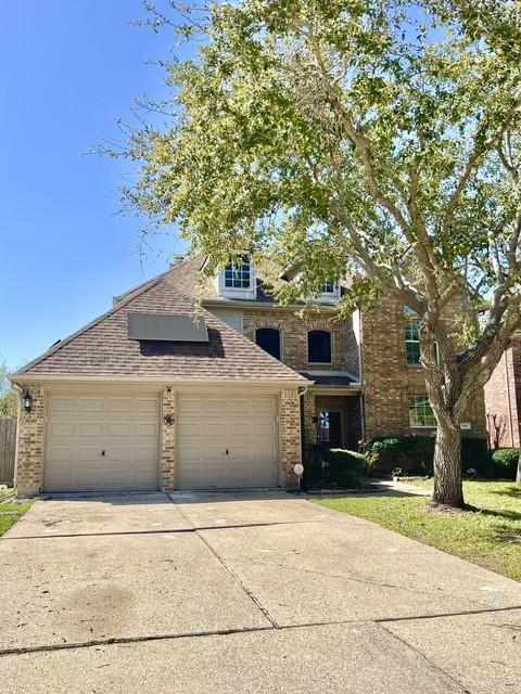 traditional home featuring an attached garage, driveway, and brick siding