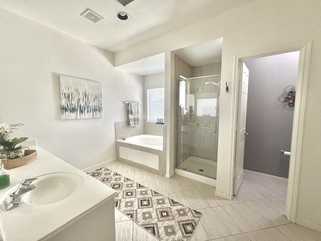 bathroom with a bath, tile patterned flooring, a stall shower, a sink, and baseboards