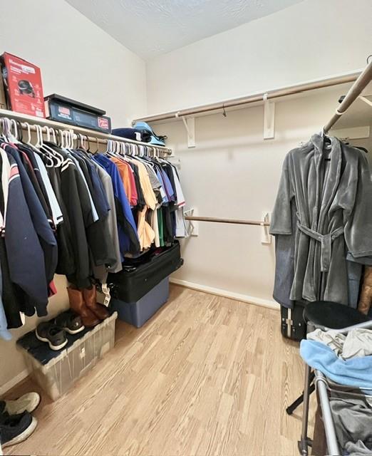 walk in closet with wood finished floors