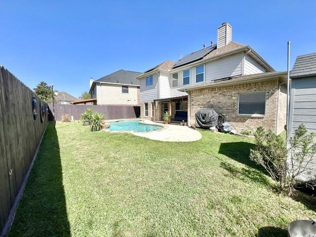 back of house with brick siding, a fenced backyard, a fenced in pool, a patio area, and a yard