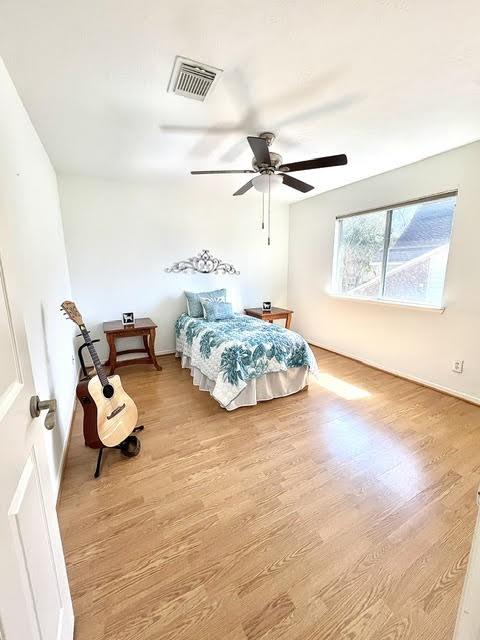 bedroom with baseboards, ceiling fan, visible vents, and wood finished floors