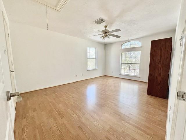 spare room featuring attic access, a ceiling fan, baseboards, wood finished floors, and visible vents