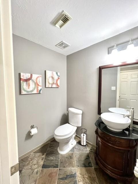 bathroom with visible vents, baseboards, toilet, and vanity