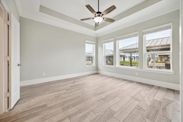 empty room featuring light wood-style floors, baseboards, a raised ceiling, and ceiling fan