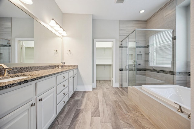full bath with a sink, a walk in closet, and a stall shower