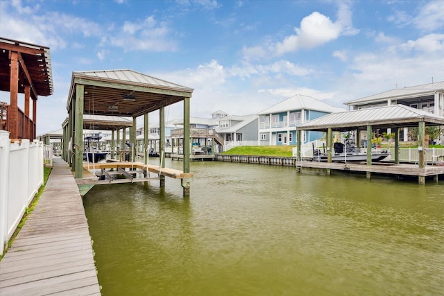 view of dock featuring a water view, a residential view, and boat lift