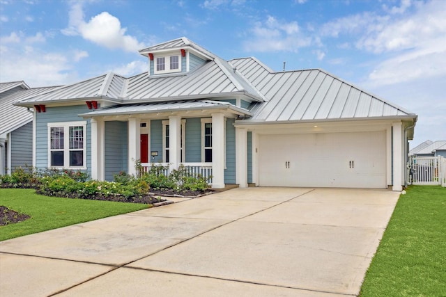 view of front of house featuring a standing seam roof, a porch, an attached garage, concrete driveway, and metal roof