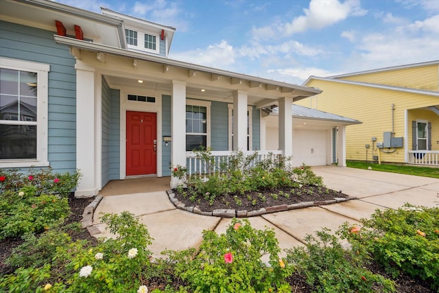 doorway to property featuring a porch, a garage, and driveway