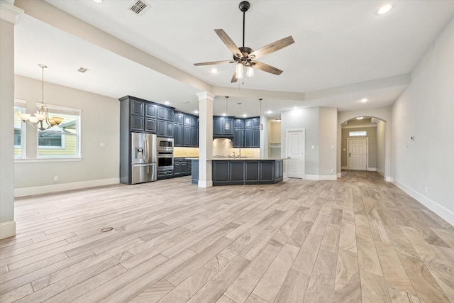 unfurnished living room with baseboards, ceiling fan with notable chandelier, visible vents, and light wood-type flooring