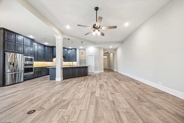 kitchen featuring arched walkways, ceiling fan, stainless steel appliances, light wood-style floors, and open floor plan