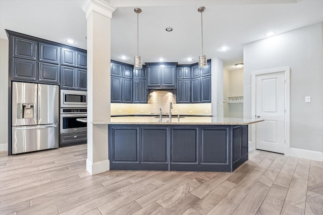 kitchen featuring wood finish floors, a sink, stainless steel appliances, blue cabinets, and tasteful backsplash