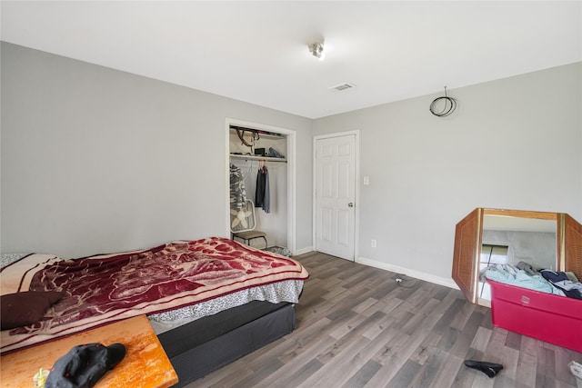 bedroom with visible vents, baseboards, a closet, and wood finished floors