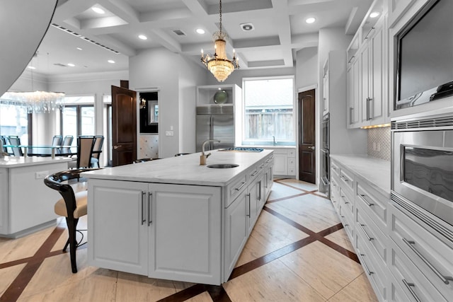 2247 Bartlett St, Houston, TX 77098 - kitchen featuring a chandelier, a kitchen island with sink, inlaid floor details, a sink, and built in appliances