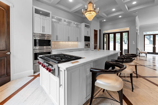 2247 Bartlett St, Houston, TX 77098 - kitchen with appliances with stainless steel finishes, inlaid floor details, a kitchen island with sink, decorative backsplash, and a chandelier