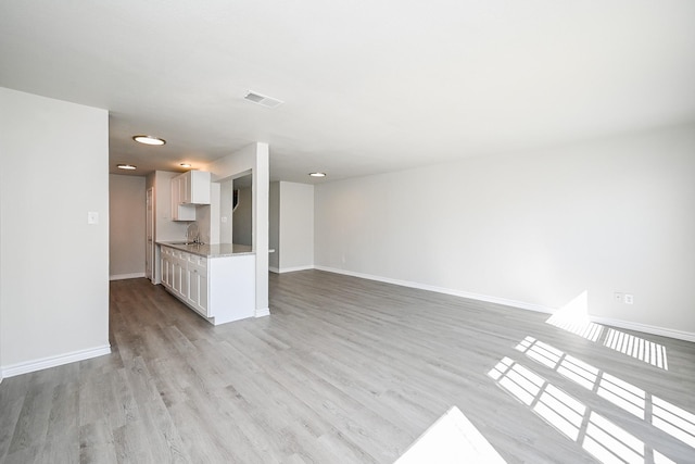 6514 Kentwick Dr, Houston, TX 77084 - unfurnished living room with a sink, visible vents, baseboards, and light wood-style flooring