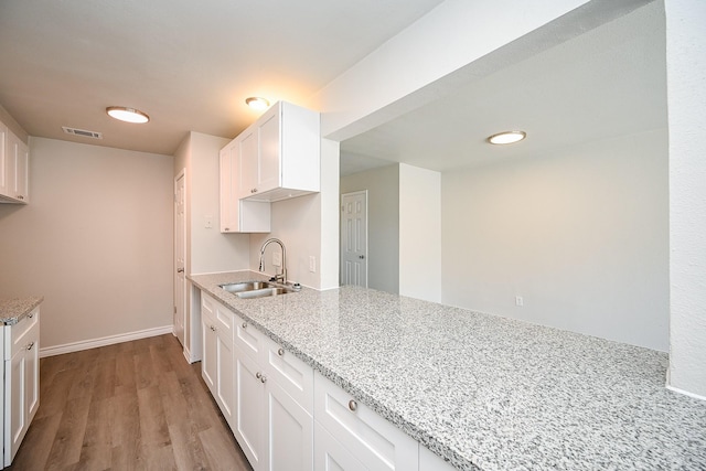 6514 Kentwick Dr, Houston, TX 77084 - kitchen with light stone countertops, a sink, white cabinetry, and visible vents