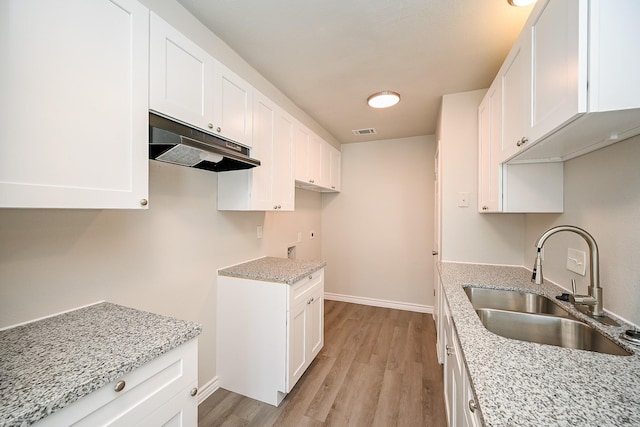 6514 Kentwick Dr, Houston, TX 77084 - kitchen with visible vents, under cabinet range hood, light stone counters, a sink, and light wood finished floors