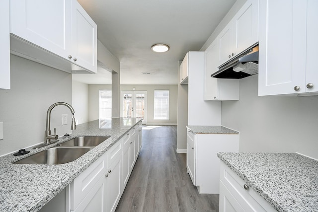 6514 Kentwick Dr, Houston, TX 77084 - kitchen featuring white cabinets, a sink, light wood-type flooring, under cabinet range hood, and light stone counters