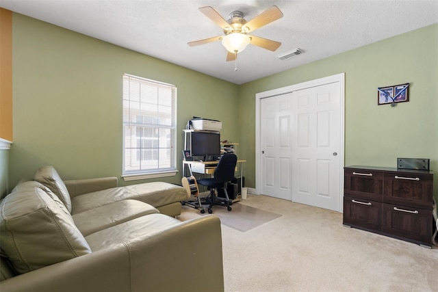 office area with light colored carpet, visible vents, and ceiling fan