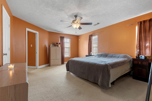 bedroom with visible vents, a ceiling fan, a textured ceiling, baseboards, and light colored carpet
