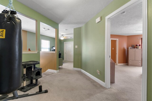 interior space with ceiling fan, carpet, baseboards, and a textured ceiling