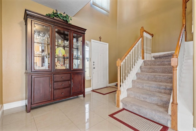 entrance foyer with light tile patterned floors, stairway, and baseboards