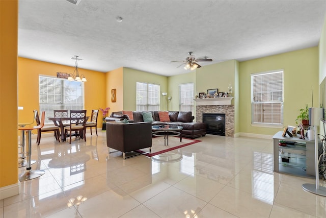 living area with light tile patterned floors, plenty of natural light, a textured ceiling, and ceiling fan with notable chandelier