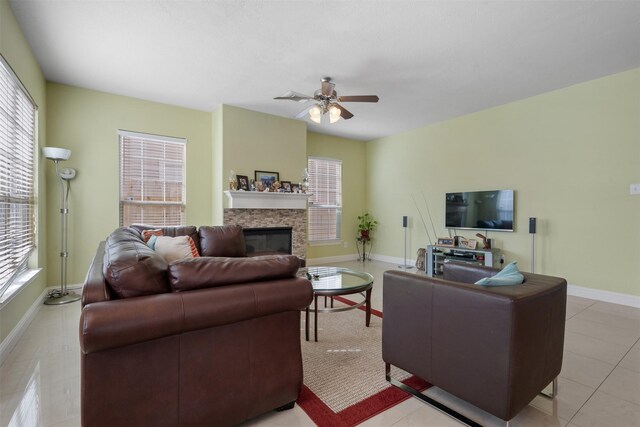 living area featuring a ceiling fan, a fireplace, baseboards, and a wealth of natural light