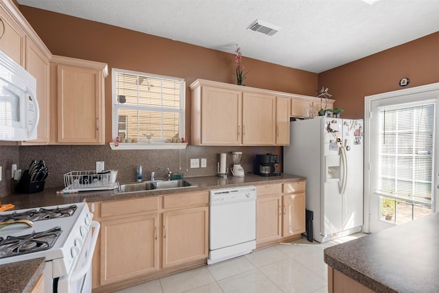 kitchen with visible vents, light brown cabinets, decorative backsplash, white appliances, and a sink