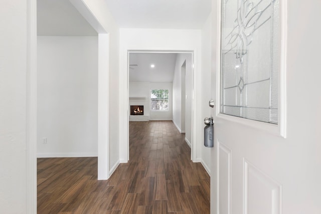 corridor with dark wood-type flooring and baseboards