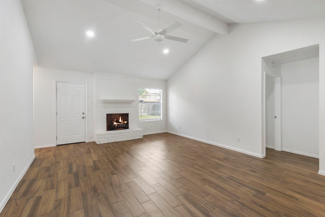unfurnished living room featuring lofted ceiling with beams, dark wood finished floors, baseboards, a brick fireplace, and ceiling fan