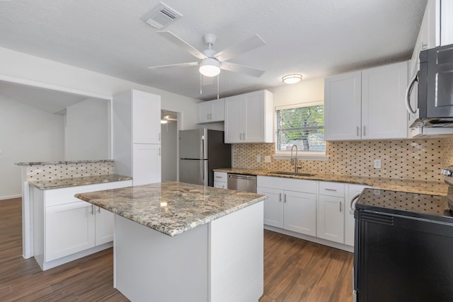 kitchen with visible vents, dark wood finished floors, a sink, stainless steel appliances, and white cabinets