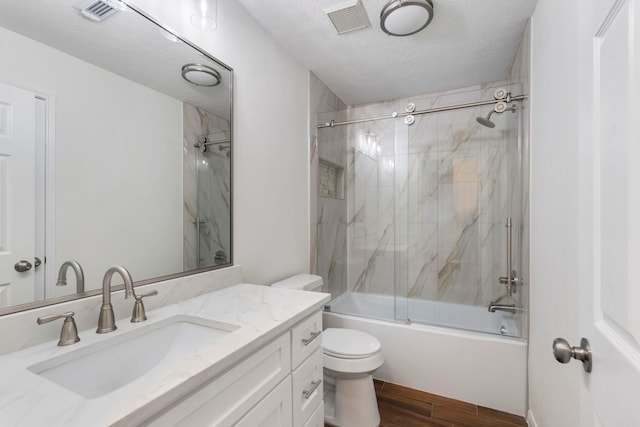 bathroom featuring visible vents, toilet, wood finished floors, and a textured ceiling