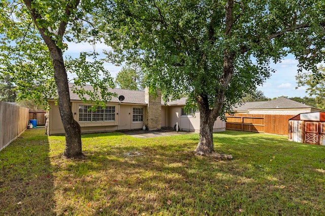 view of yard with a storage unit, a patio, an outdoor structure, and a fenced backyard