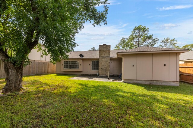 back of property with a patio area, a fenced backyard, a lawn, and a chimney