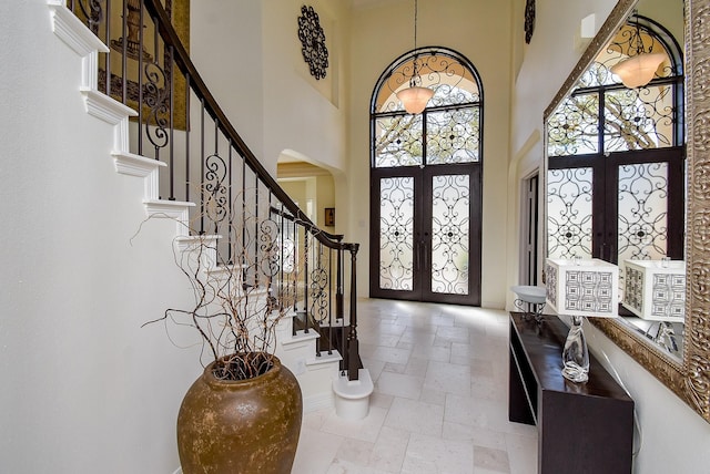 entrance foyer with french doors, arched walkways, stone tile flooring, and stairway