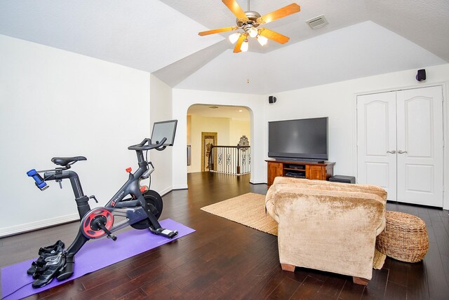 exercise area with visible vents, vaulted ceiling, wood finished floors, arched walkways, and a ceiling fan