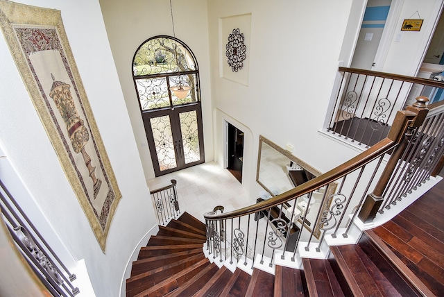 entrance foyer featuring french doors, a high ceiling, stairs, and hardwood / wood-style flooring