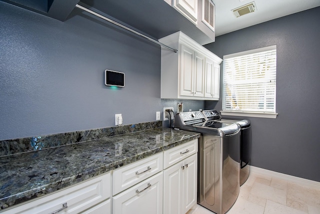 clothes washing area featuring visible vents, stone tile floors, cabinet space, separate washer and dryer, and baseboards
