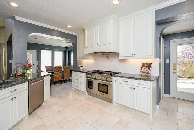 kitchen with stone tile floors, white cabinetry, recessed lighting, stainless steel appliances, and arched walkways