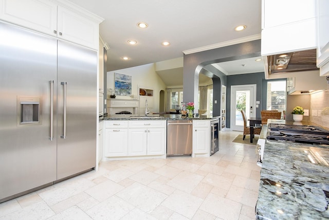 kitchen with dark stone countertops, white cabinets, beverage cooler, and stainless steel appliances