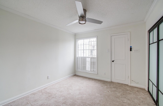 empty room featuring light carpet, a textured ceiling, ornamental molding, and a ceiling fan