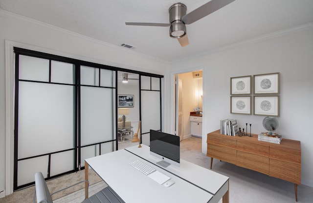 home office featuring visible vents, light colored carpet, ornamental molding, and a ceiling fan