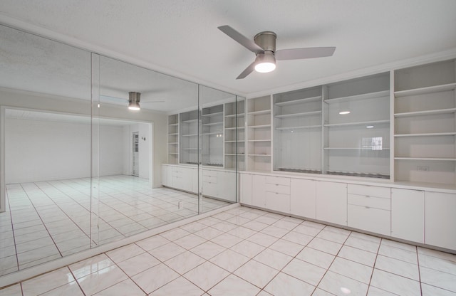 empty room featuring built in shelves, a textured ceiling, ceiling fan, and light tile patterned flooring