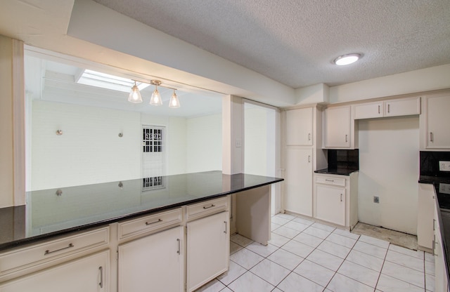 kitchen with hanging light fixtures, dark countertops, light tile patterned flooring, and a textured ceiling