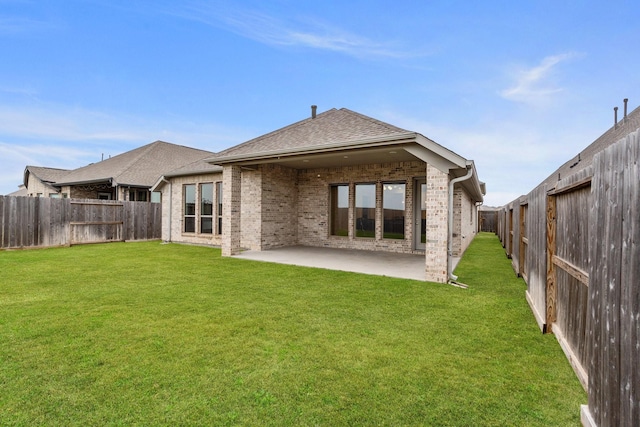 back of property featuring brick siding, a patio area, a lawn, and a fenced backyard