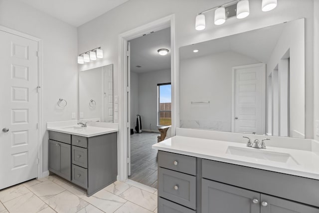 bathroom with a sink, baseboards, and two vanities