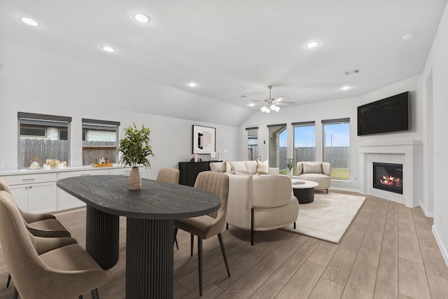 dining room with lofted ceiling, recessed lighting, ceiling fan, a glass covered fireplace, and light wood-type flooring