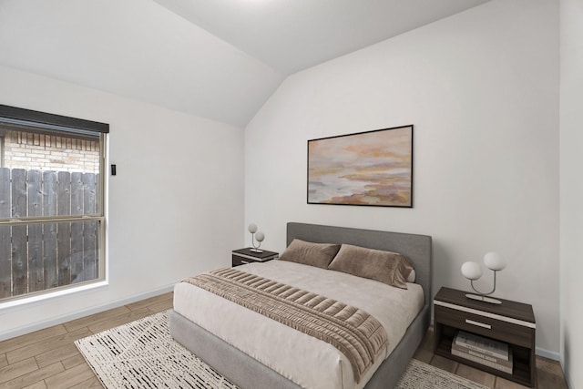 bedroom featuring lofted ceiling, wood finished floors, and baseboards